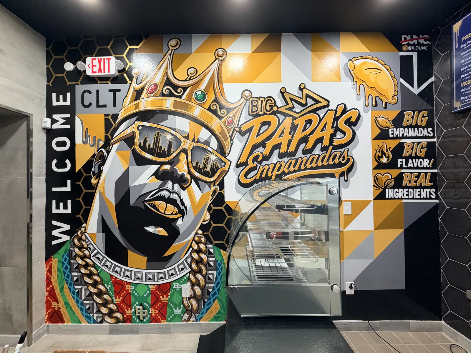 Hand-painted mural inside Big Papa’s: a crowned portrait in gold and black, the Big Papa’s logo, and the words Big Empanadas, Big Flavor, Real Ingredients